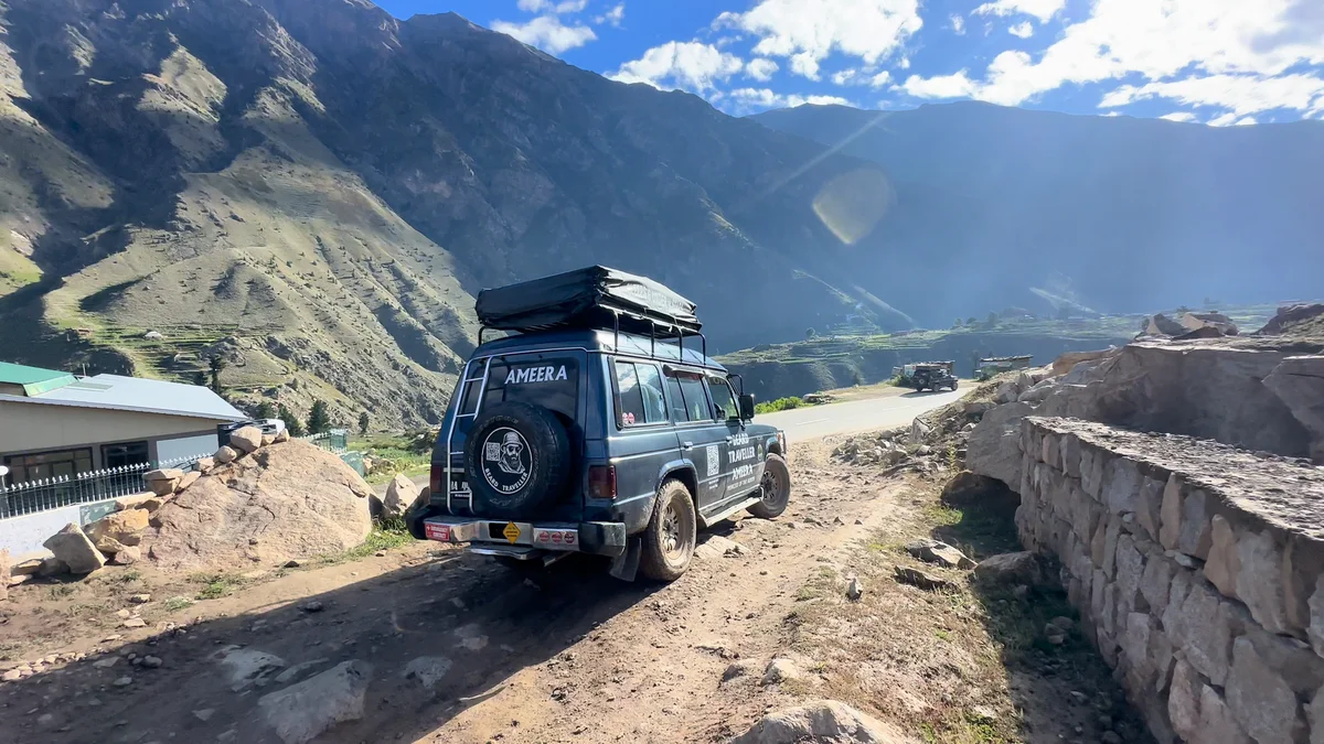 Ameera with her rooftop tent on a mountain track above a green valley