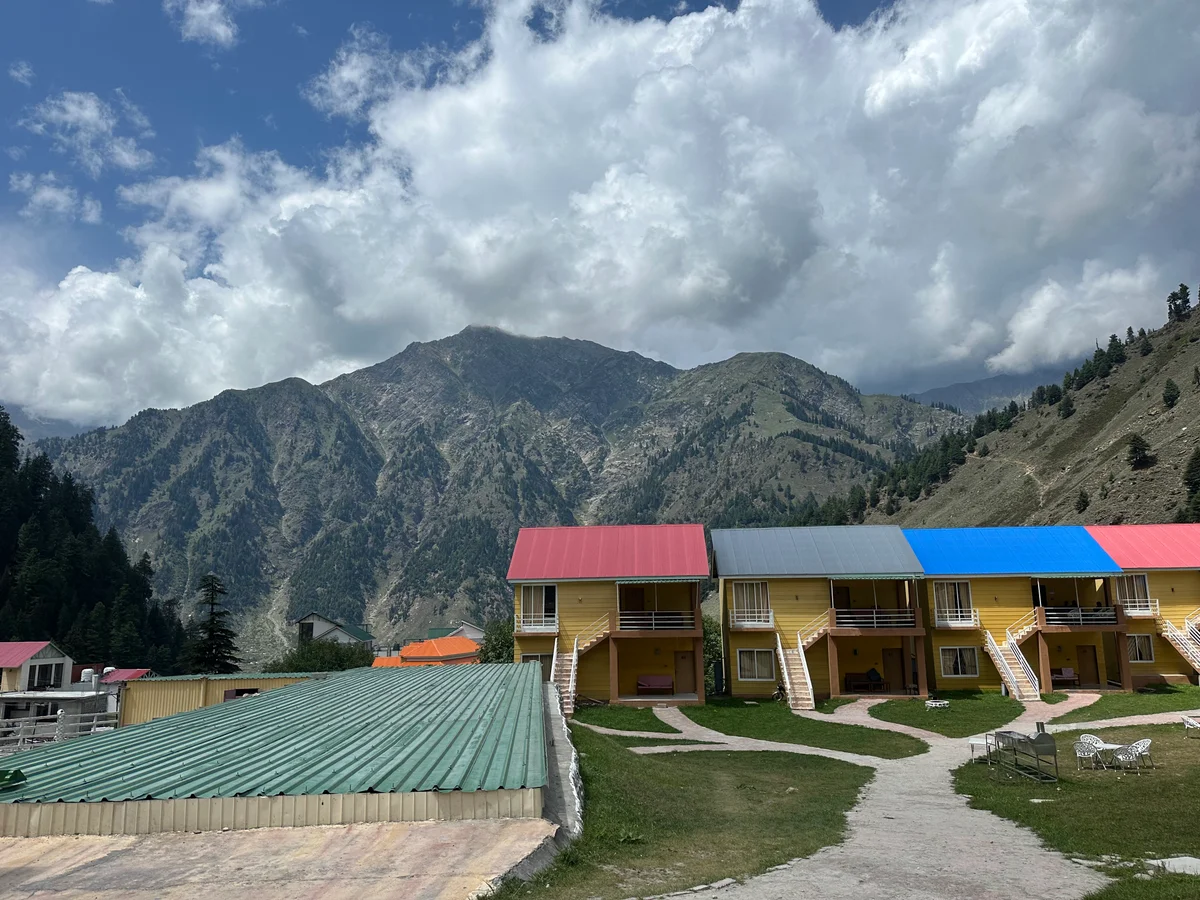 Colourful mountain cabins beneath a dramatic cloudy sky