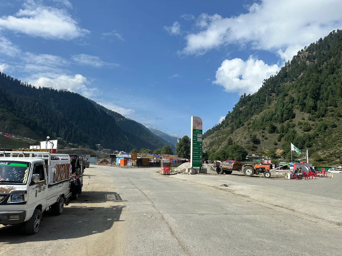 Mountain transport and roadside stops beneath pine-covered valley slopes