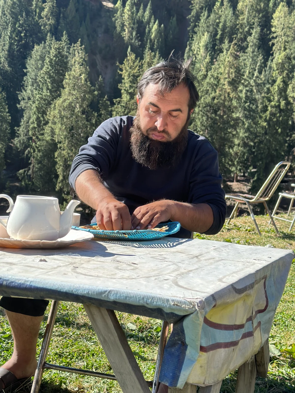 Abdullah sharing a quiet outdoor meal with a forest behind him