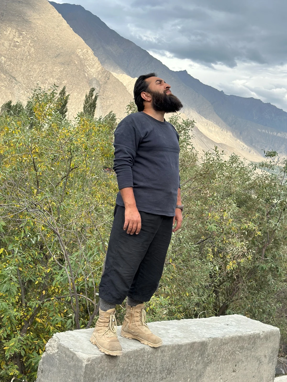Abdullah standing on a rock, looking towards the mountain sky