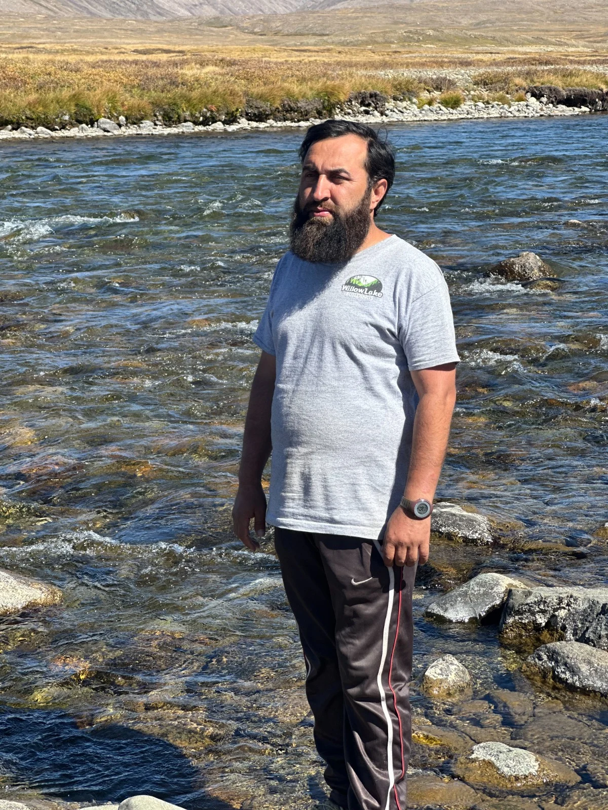 Abdullah standing beside a flowing stream and an open mountain plateau